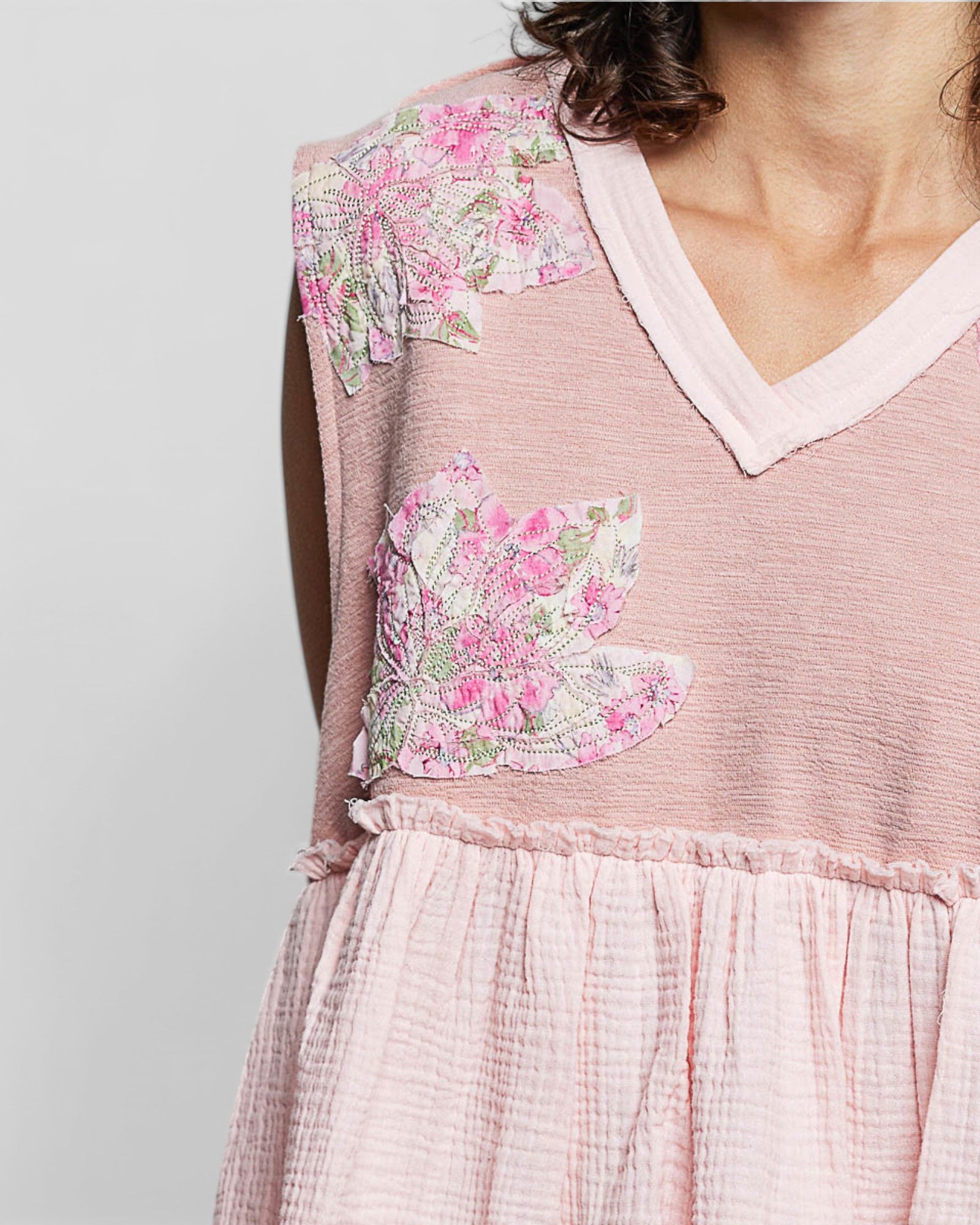 Pink dress with floral butterfly patches on a plain background