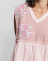 Pink dress with floral butterfly patches on a plain background