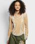Woman wearing a beige long-sleeve top with floral details on a plain background