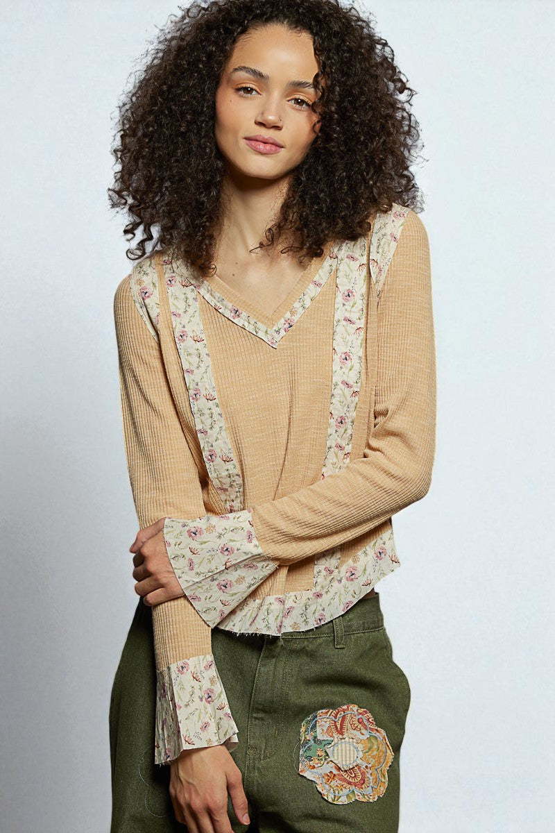 Woman wearing a beige sweater with floral patterns on a plain background