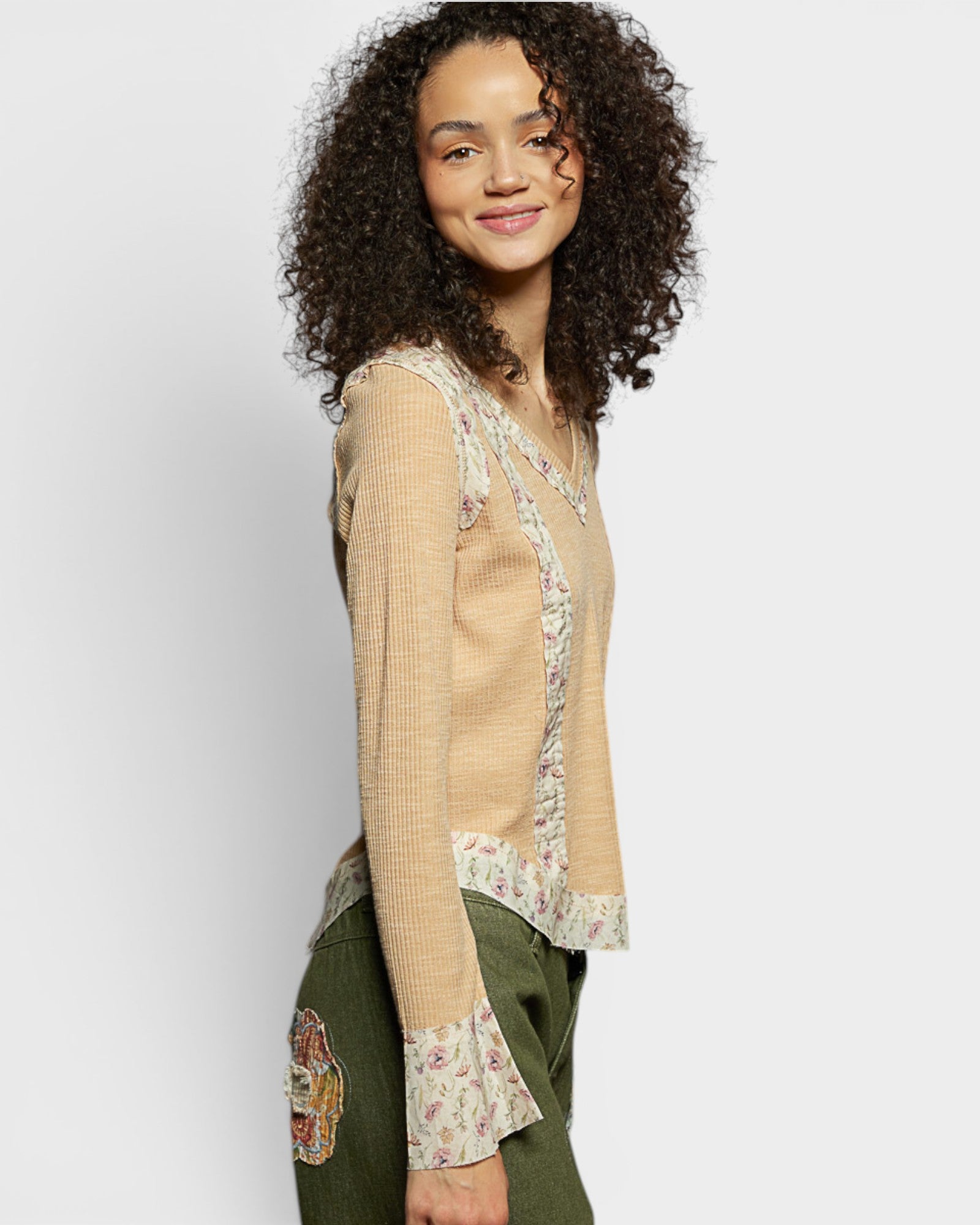 Woman wearing a beige blouse with floral patterns on a plain background