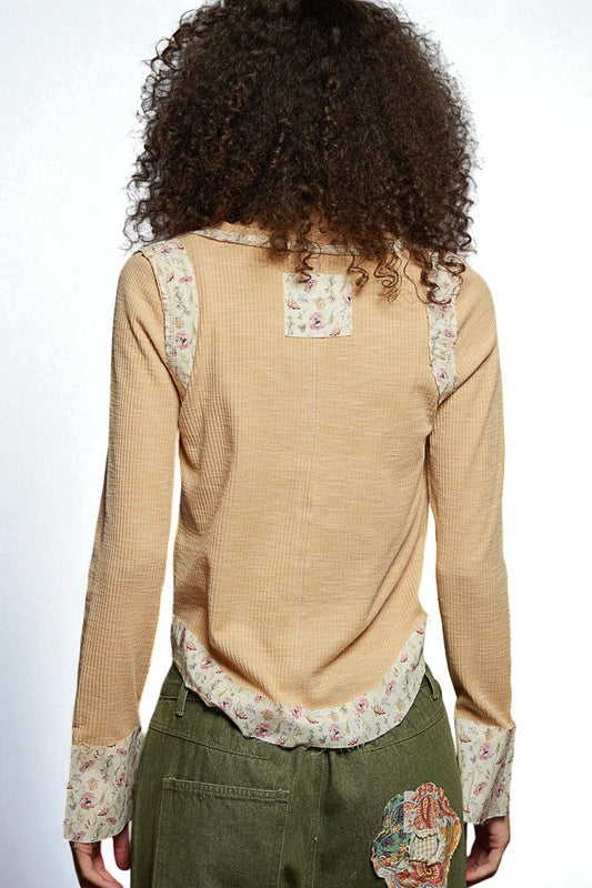 Woman wearing a beige blouse with floral patterns on a white background