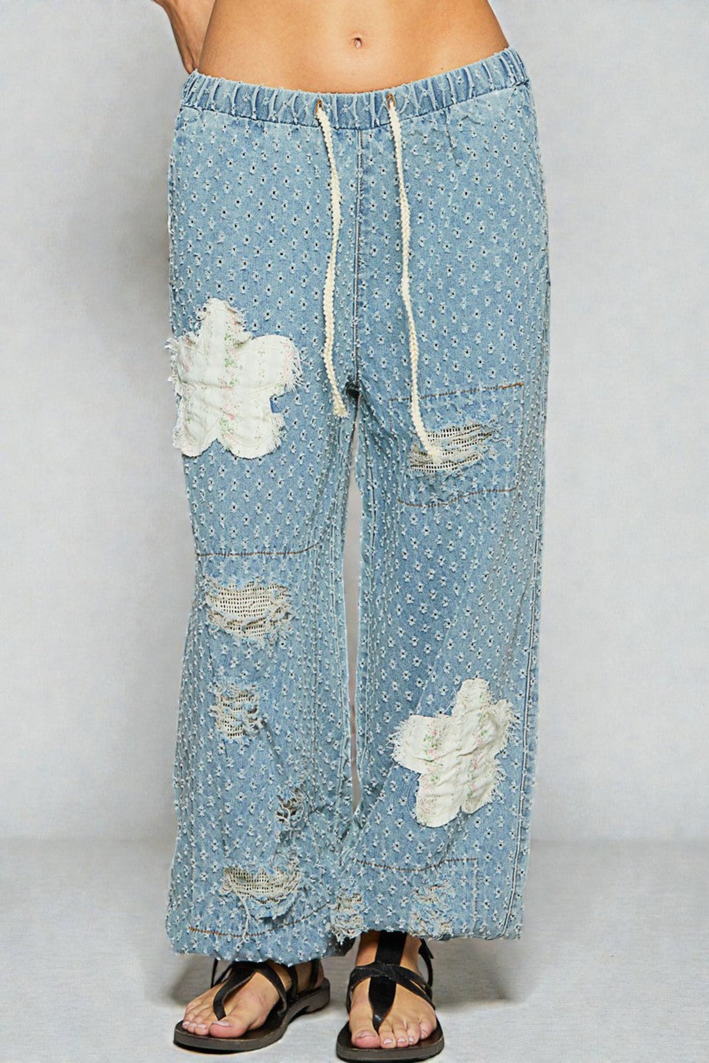 Light blue denim pants with cloud patterns and drawstring on a white background