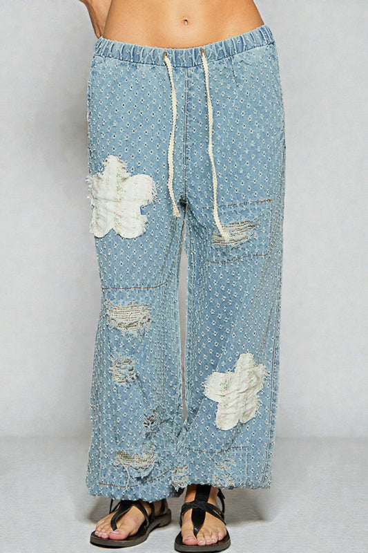 Light blue denim pants with cloud patterns and drawstring on a white background