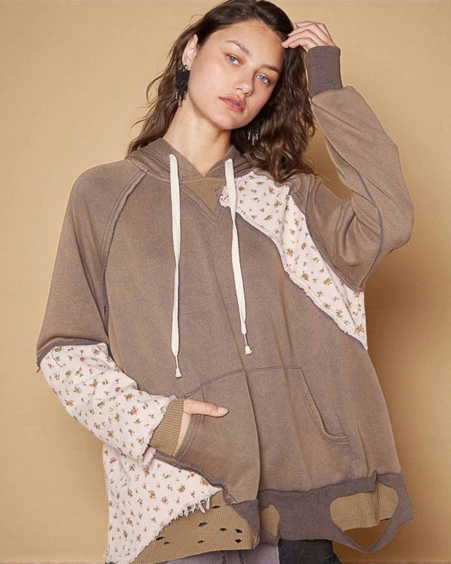 Woman wearing a brown hoodie with floral patterns on a beige background