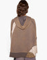 A person shown from the back wearing a brown patchwork poncho-style top with a cowl neck, solid brown base, and cream patterned side panels, against a plain light background.