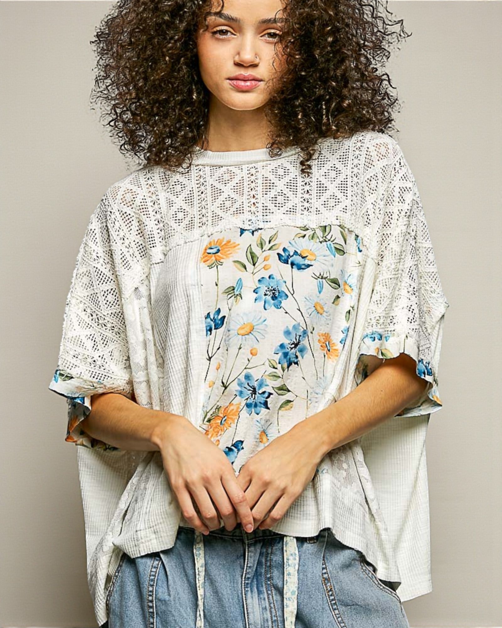 Woman wearing a floral blouse with a lace overlay against a neutral background
