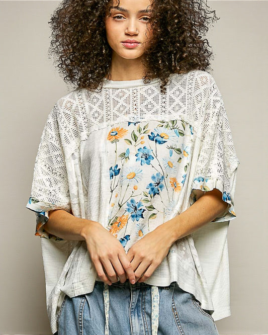 Woman wearing a floral blouse with a lace overlay against a neutral background