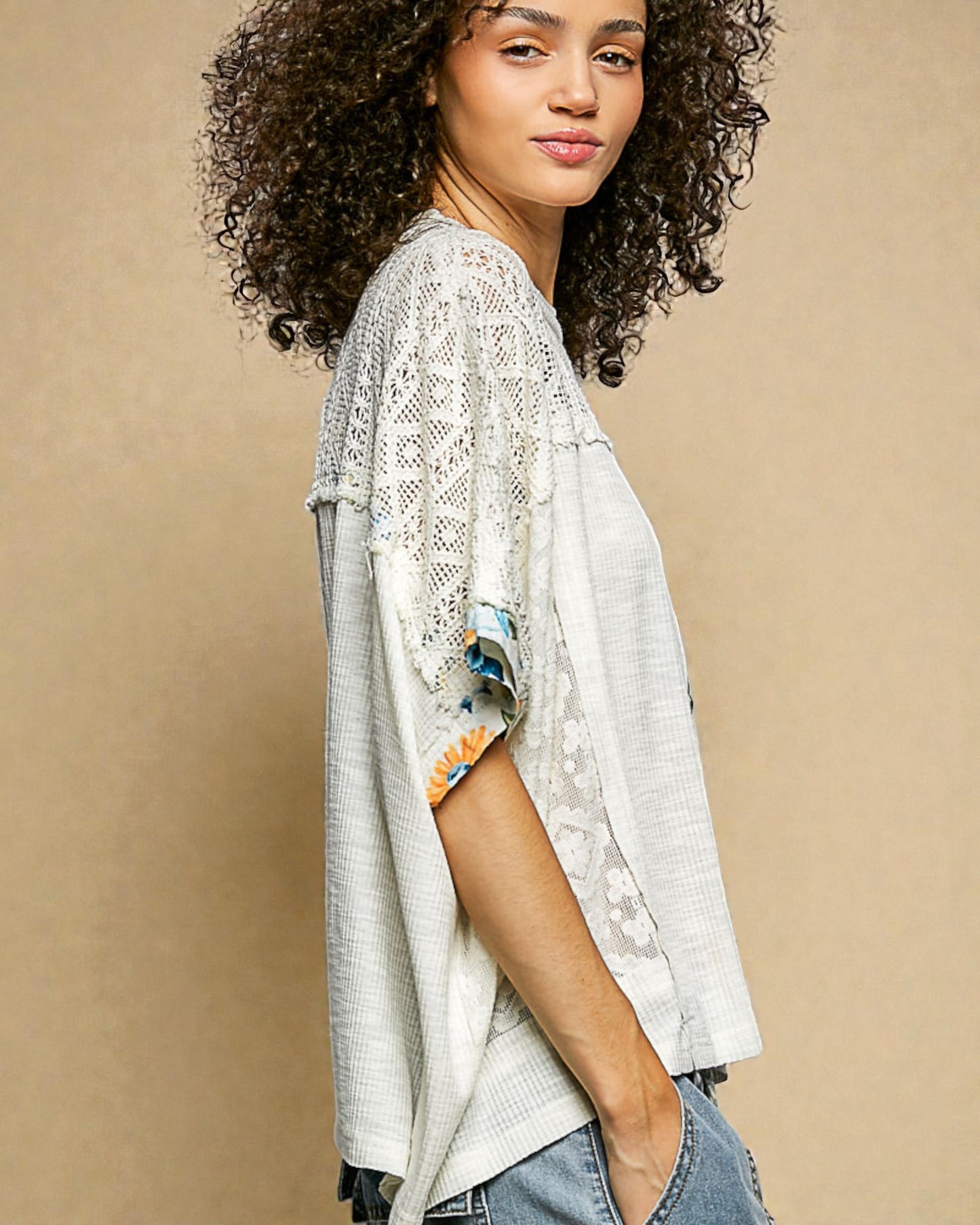 Woman wearing a light gray lace kimono-style top against a beige background
