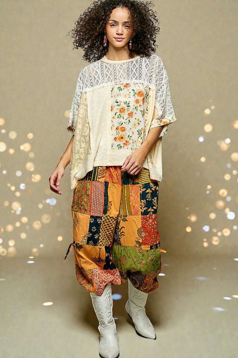 Woman wearing a floral top and patchwork skirt with white boots on a beige background
