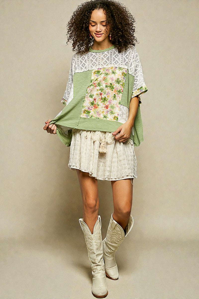 Woman wearing a green and white dress with floral patterns and white cowboy boots on a beige background