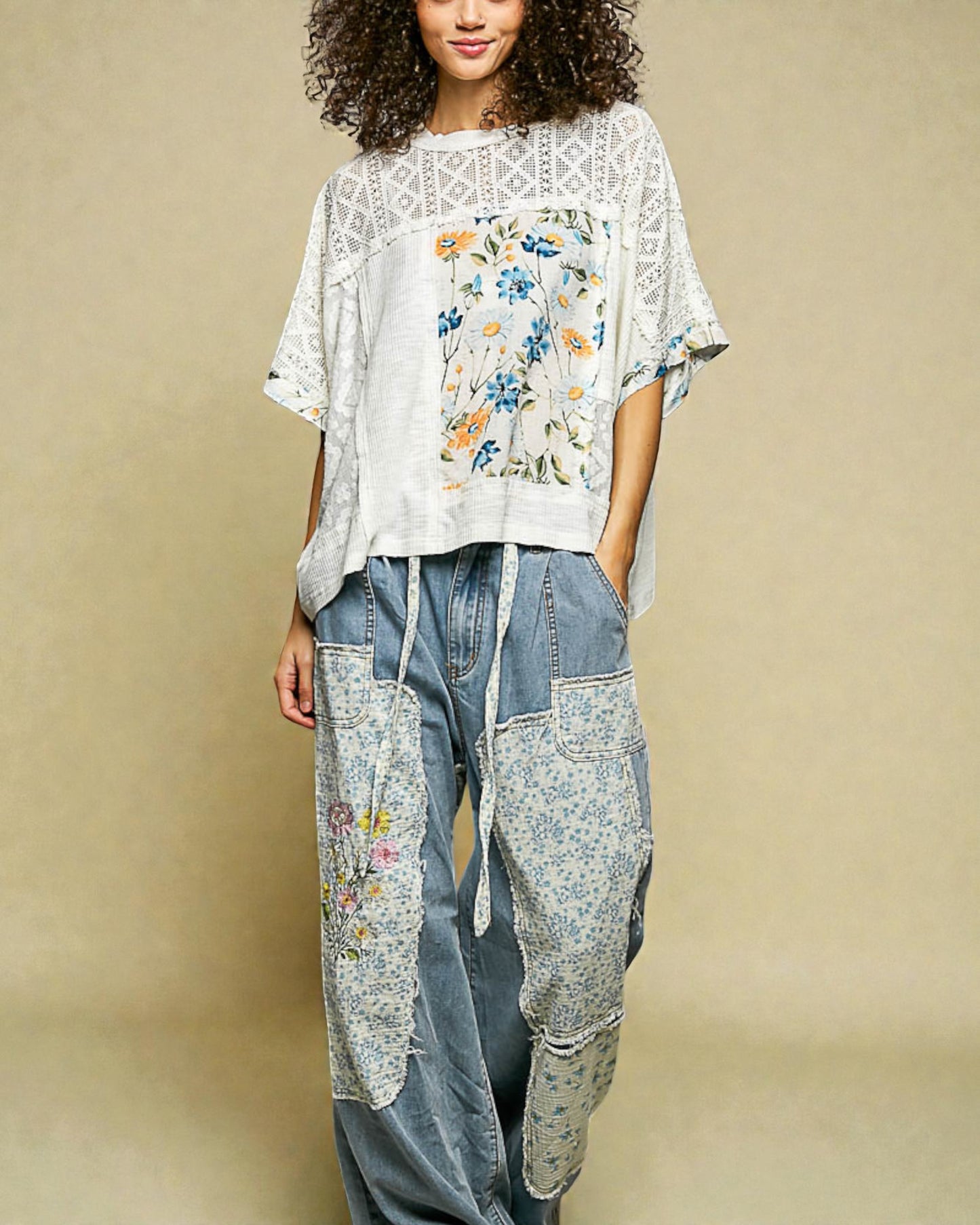 Woman wearing a floral top and denim pants on a beige background