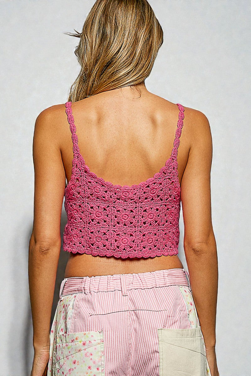 Person wearing a pink crochet top and pink pants against a plain background