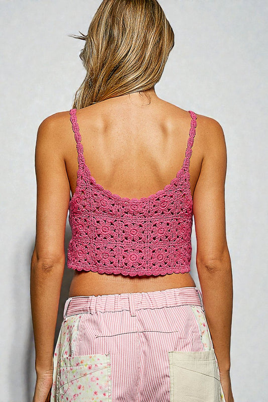 Person wearing a pink crochet top and pink pants against a plain background