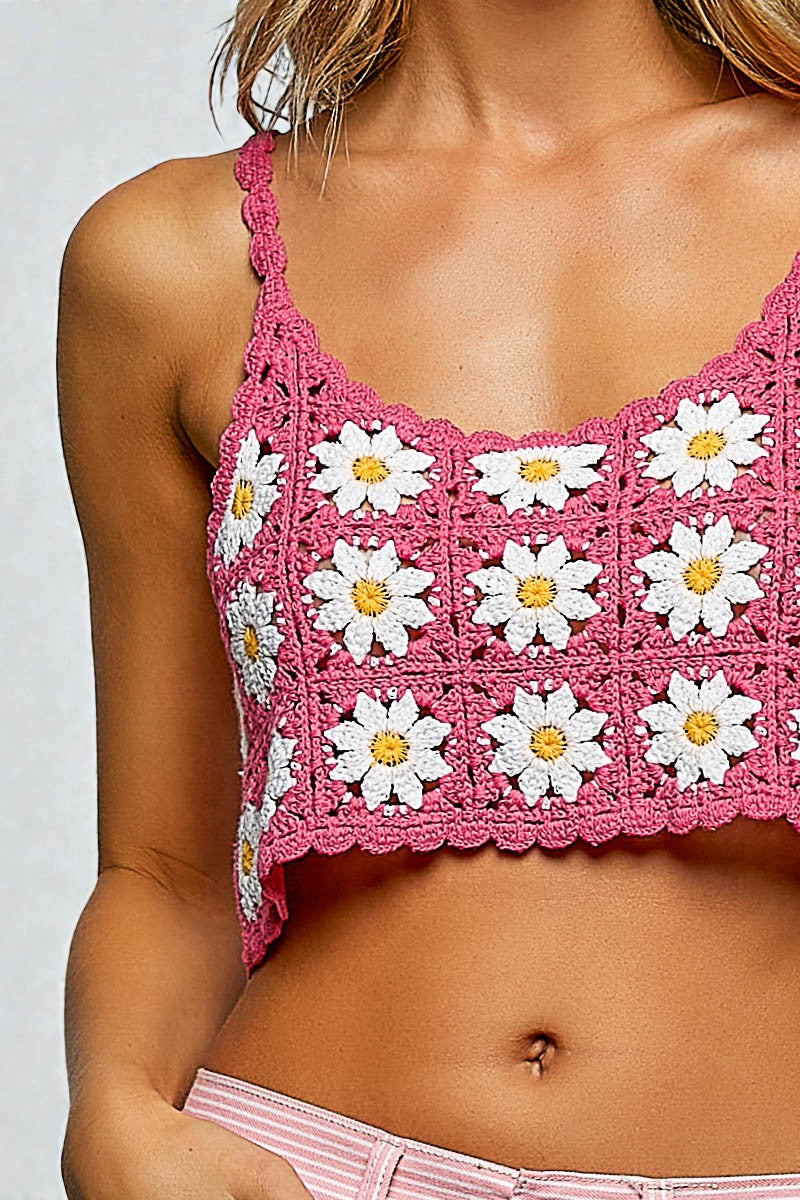 Pink crochet top with white daisy patterns on a plain background