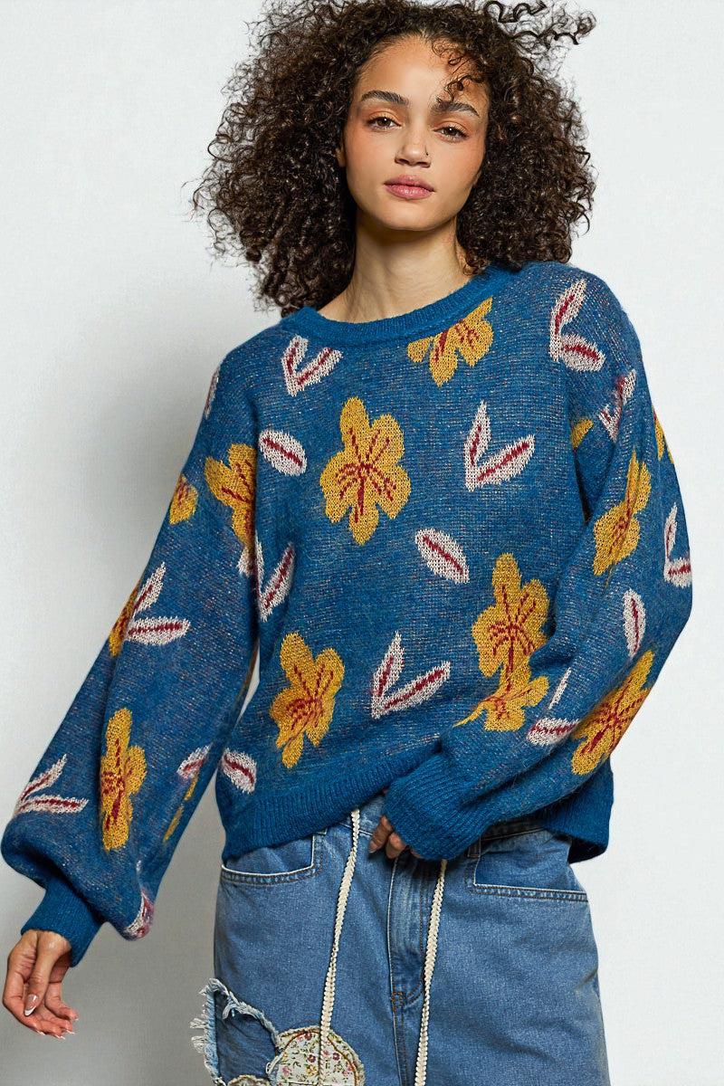 Woman wearing a blue sweater with floral patterns on a white background