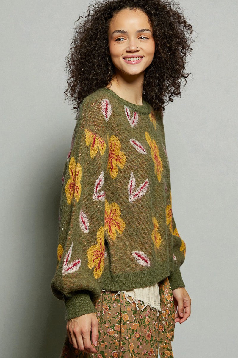 Woman wearing a green sweater with floral patterns against a plain background