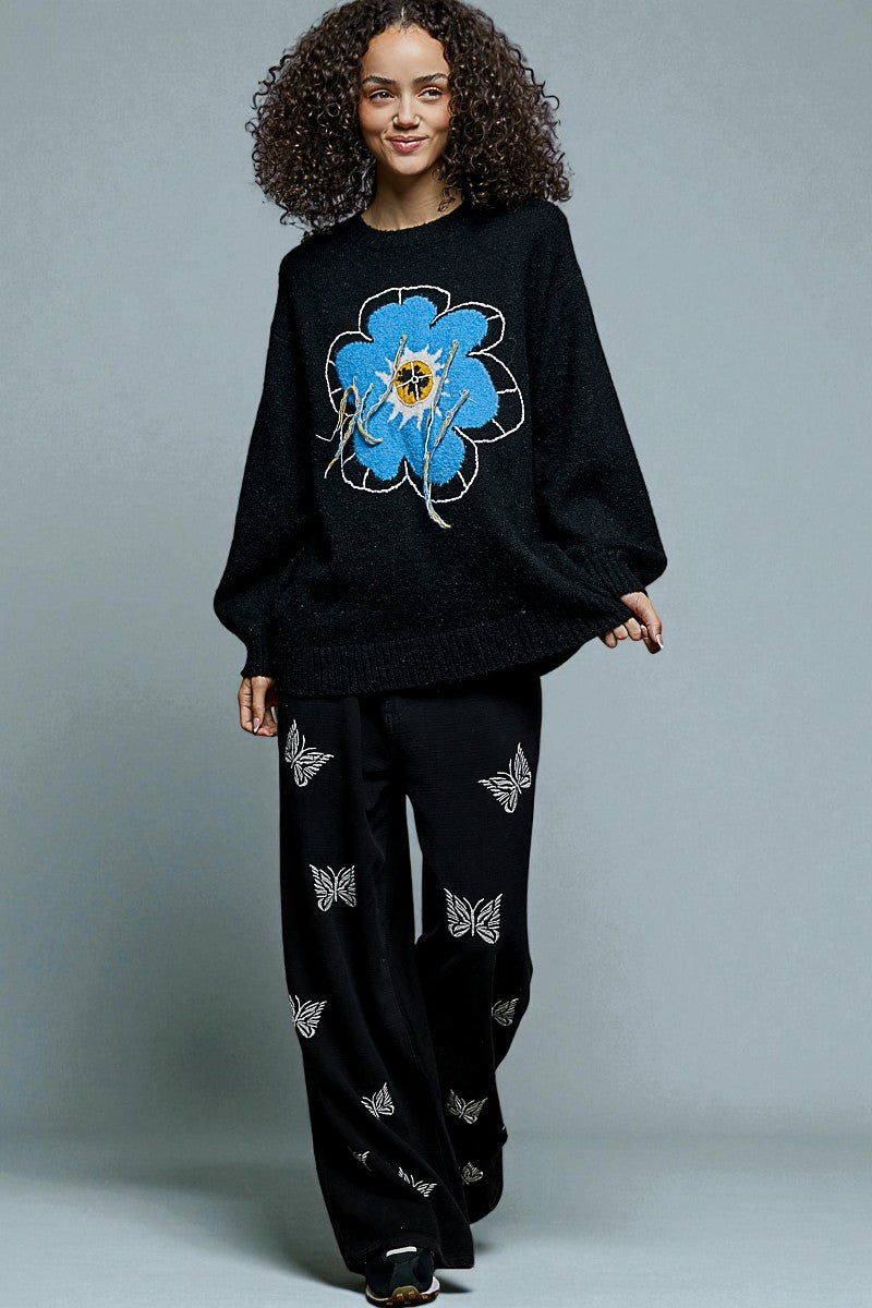 Person wearing a black outfit with a blue floral design on a gray background