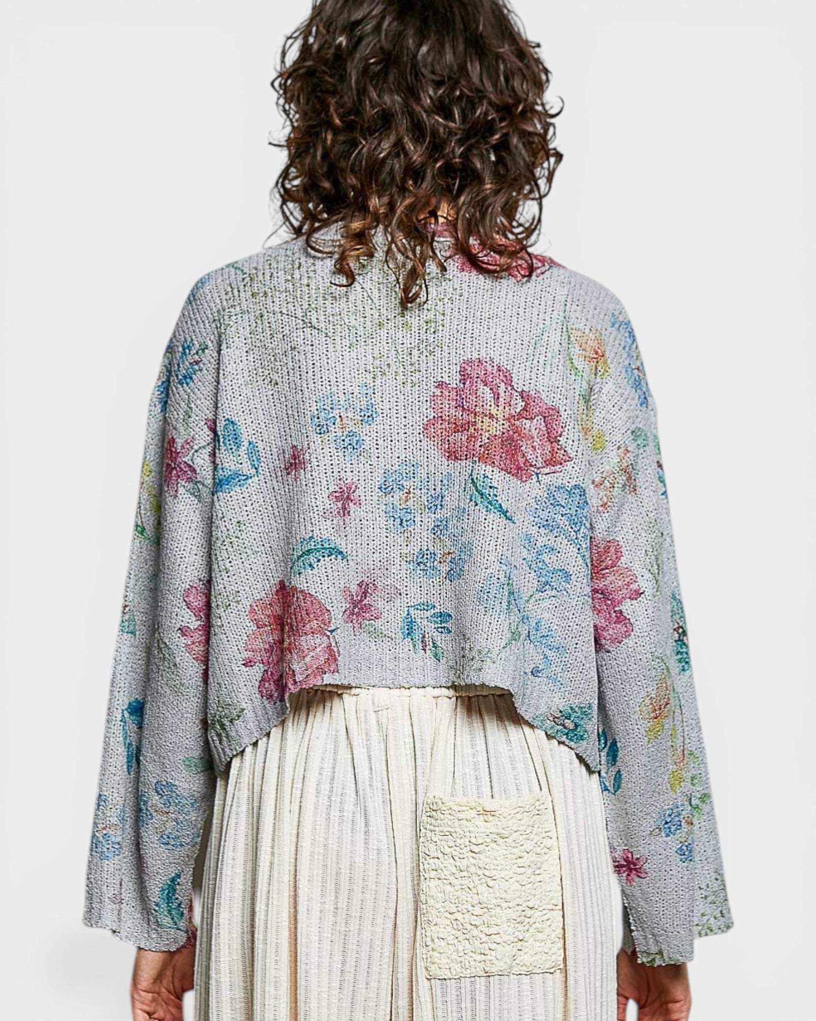 Person wearing a floral-patterned cardigan on a white background