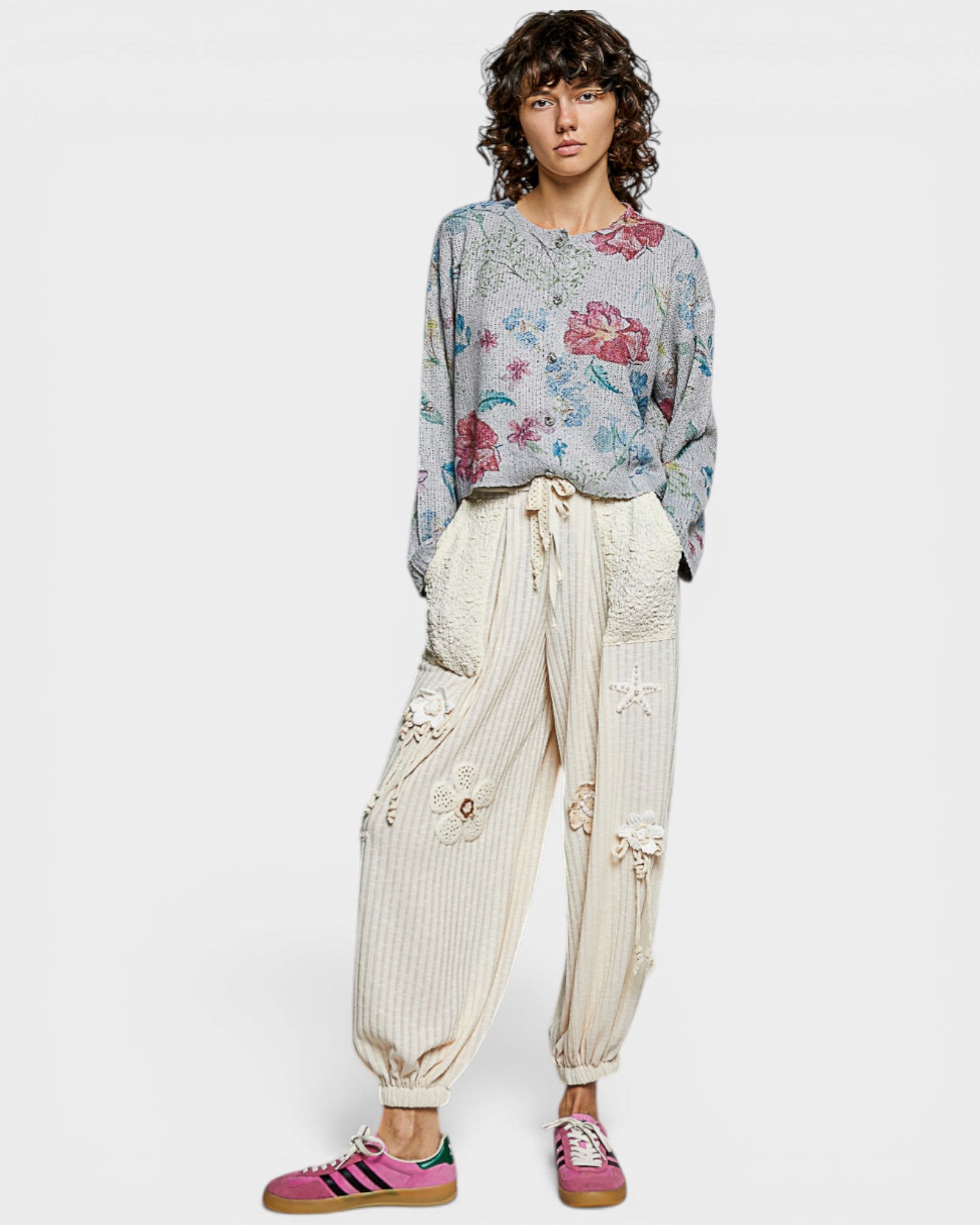 Person wearing a floral blouse and beige pants on a white background
