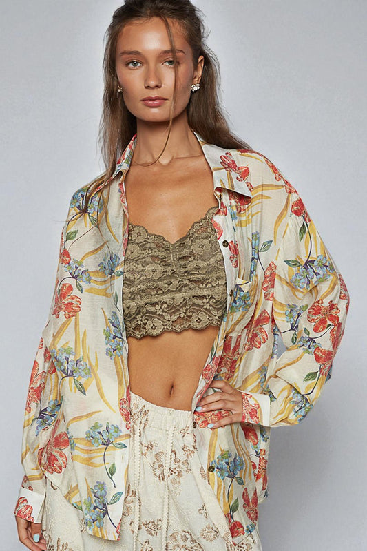 Woman wearing a floral kimono over a lace top and white pants on a plain background