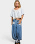 Woman wearing a light blue patterned top and denim baggy pants on a white background
