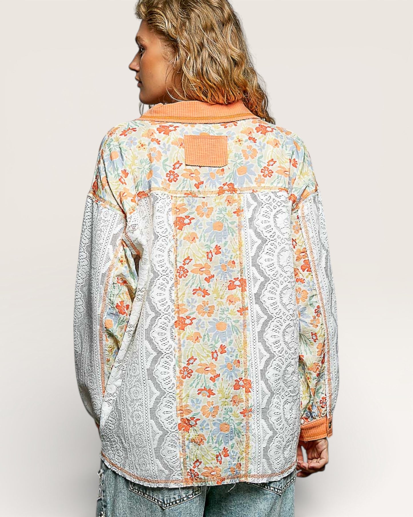 Person wearing a floral and lace patterned jacket on a plain background