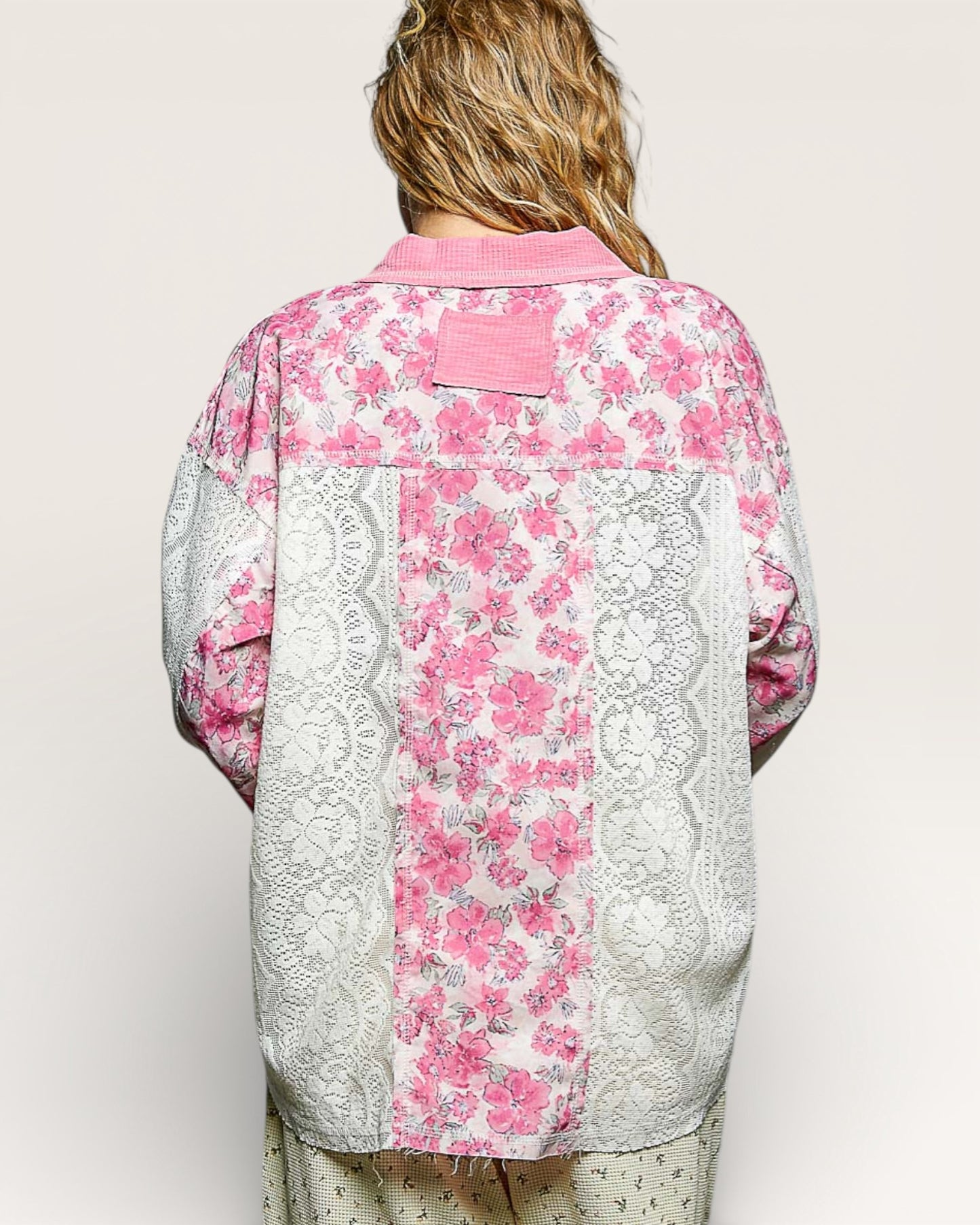 Person wearing a pink floral kimono-style garment with lace details on a plain background