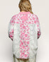 Person wearing a pink floral kimono-style garment with lace details on a plain background