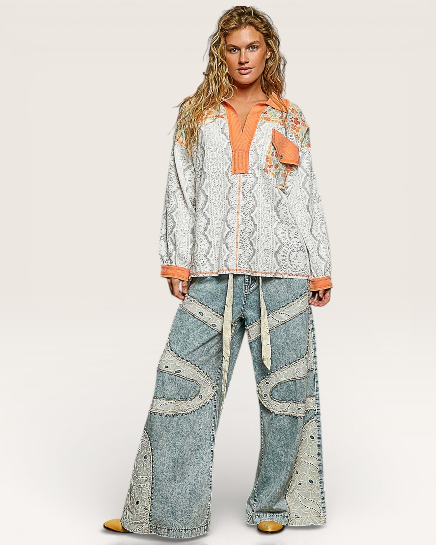 Woman wearing a patterned top and denim pants on a white background