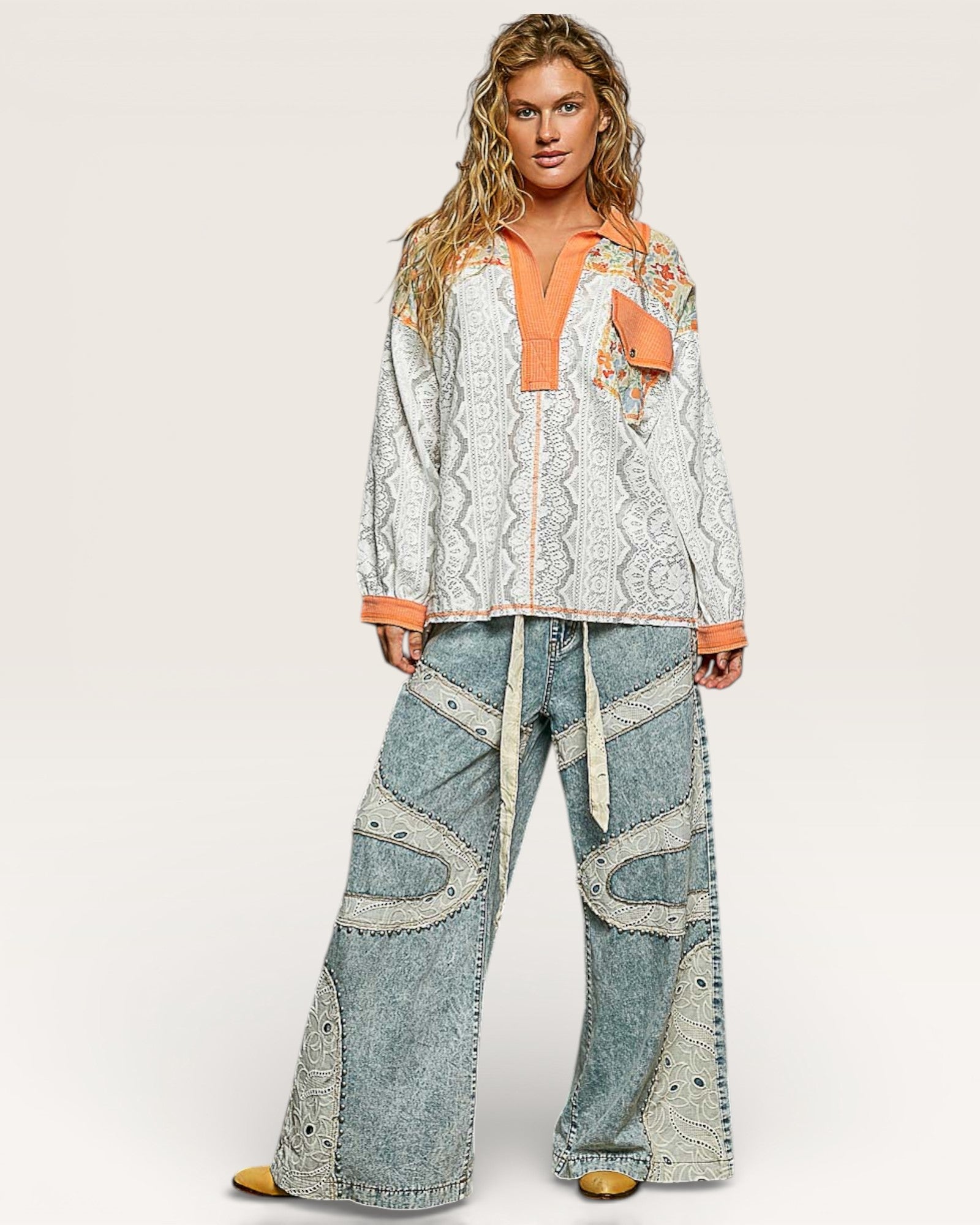 Woman wearing a patterned top and denim pants on a white background