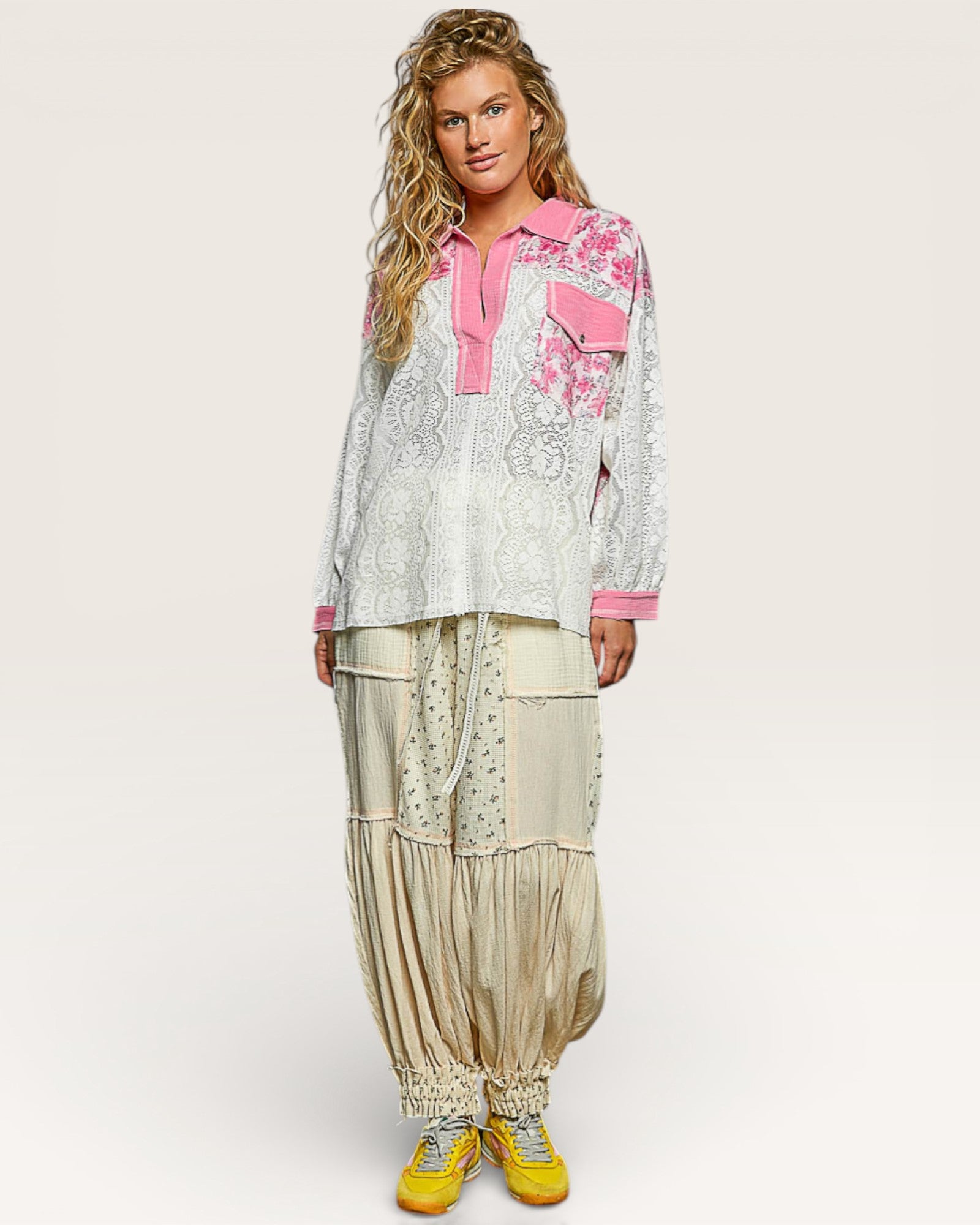 Woman wearing a floral blouse with pink accents and beige pants on a white background