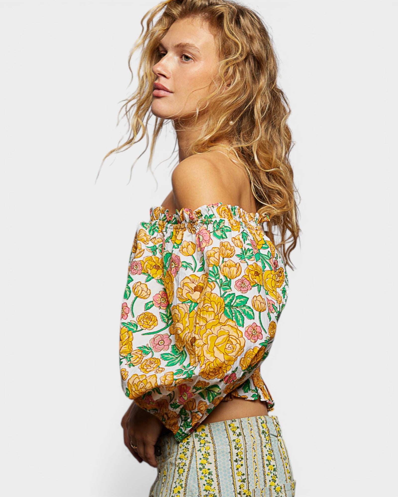 Woman wearing a floral off-shoulder top with a plain background