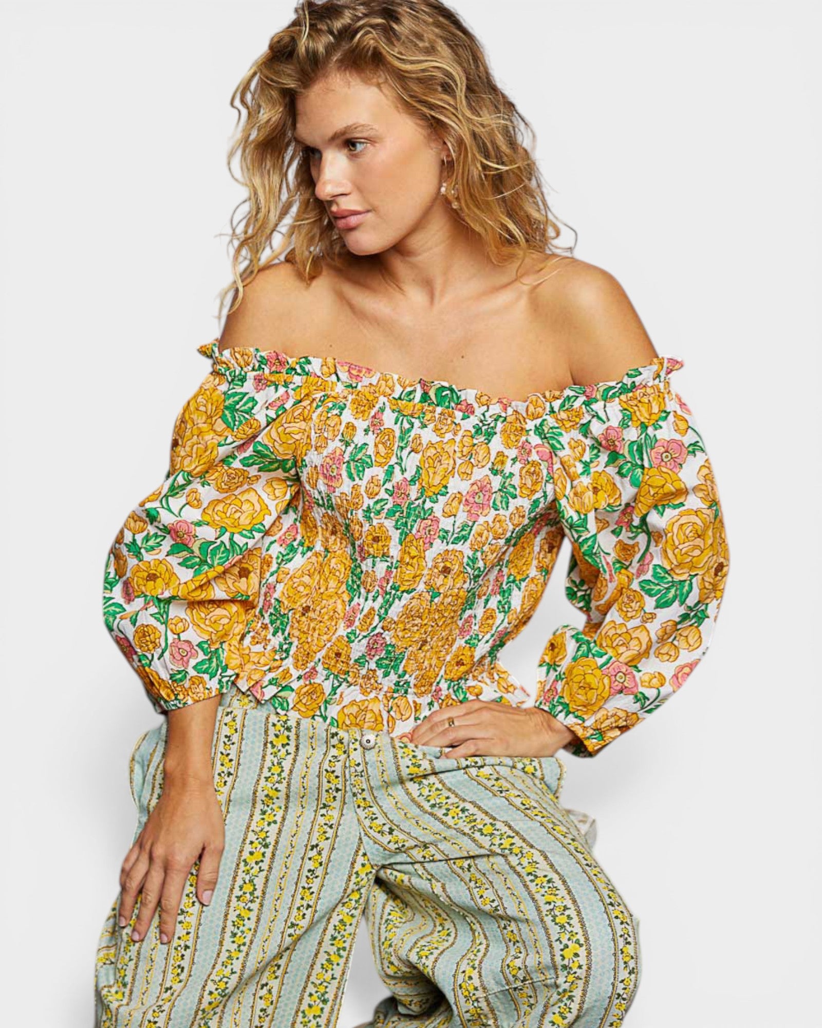 Woman wearing a floral off-shoulder top with matching pants on a white background