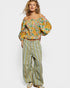 Woman wearing a floral off-shoulder top and wide-leg pants on a white background