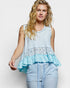 Woman wearing a light blue sleeveless top with ruffled layers on a white background
