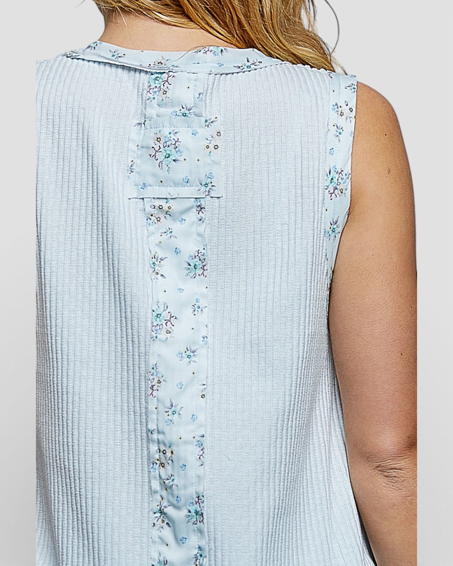 Light blue sleeveless top with floral pattern on a plain background