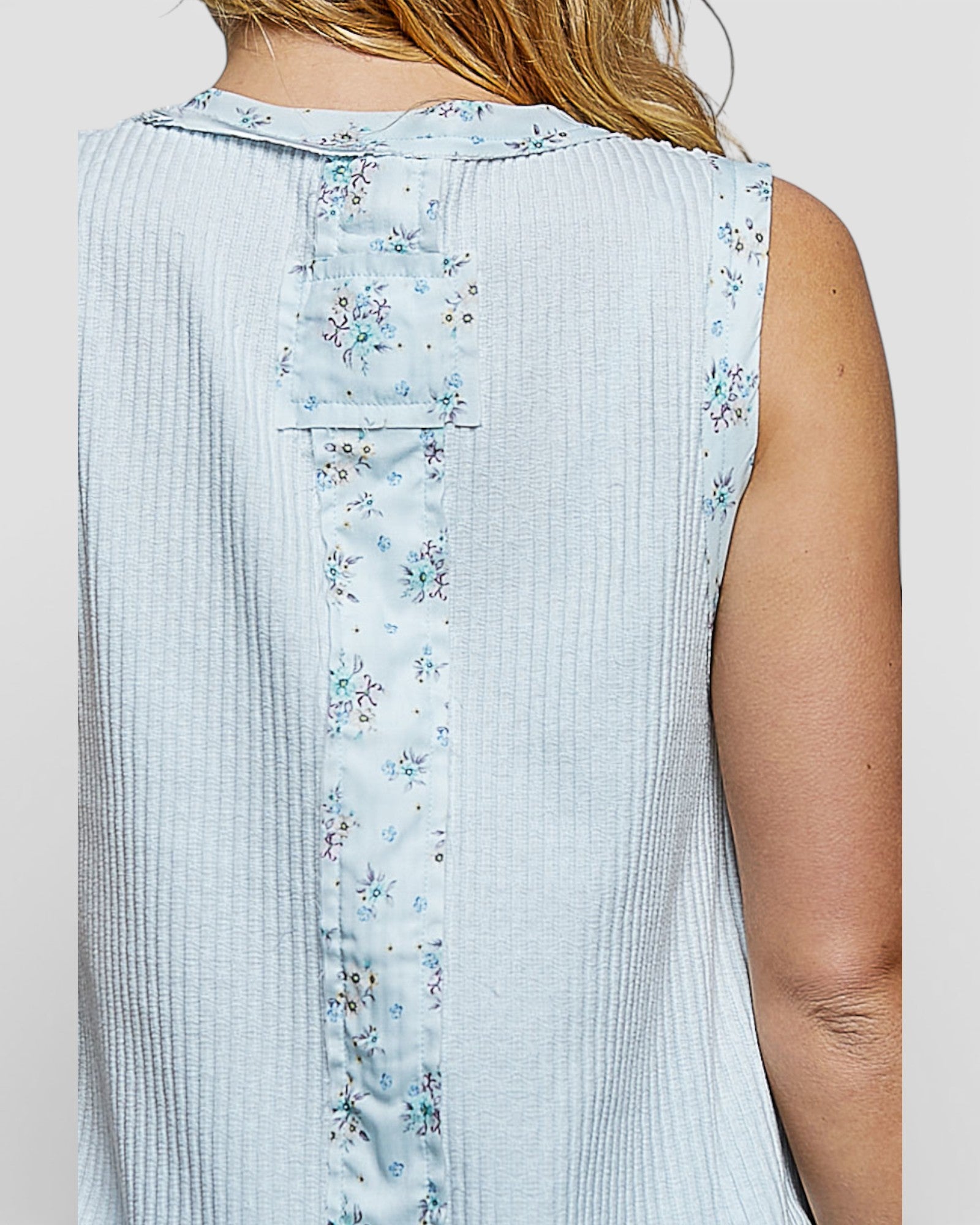 Light blue sleeveless top with floral pattern on a plain background