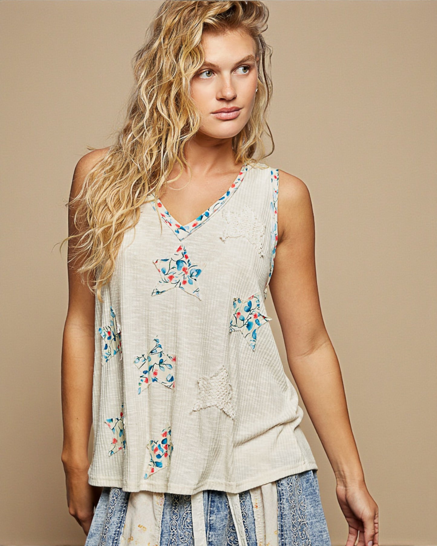Woman wearing a sleeveless top with floral patterns on a beige background