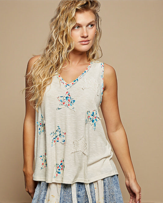 Woman wearing a sleeveless top with floral patterns on a beige background