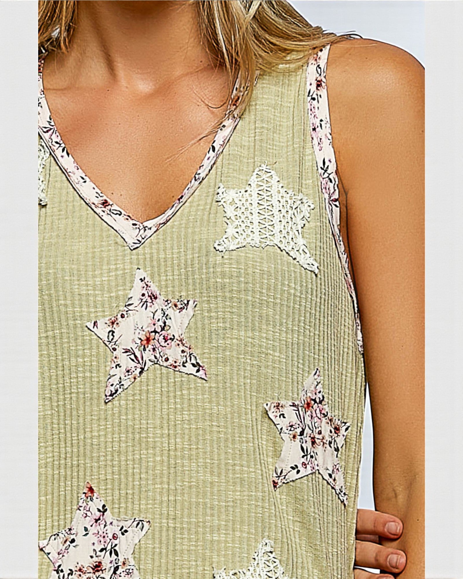 Green sleeveless top with star-shaped floral patches on a plain background