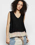 Woman wearing a black sleeveless top with a ruffled bottom on a white background