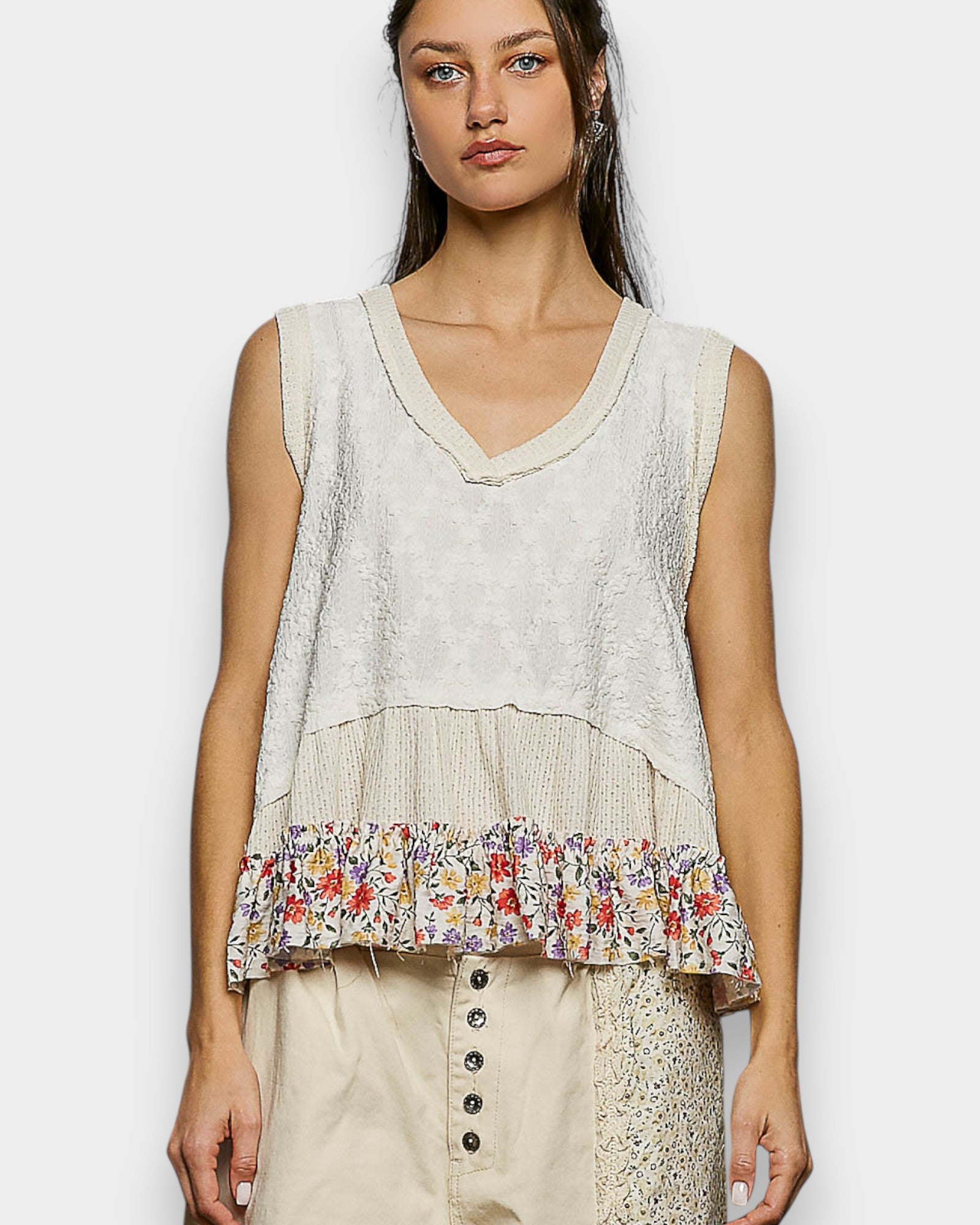 Woman wearing a sleeveless top with floral pattern on a plain background