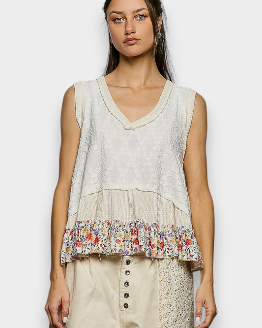 Woman wearing a sleeveless top with floral pattern on a plain background