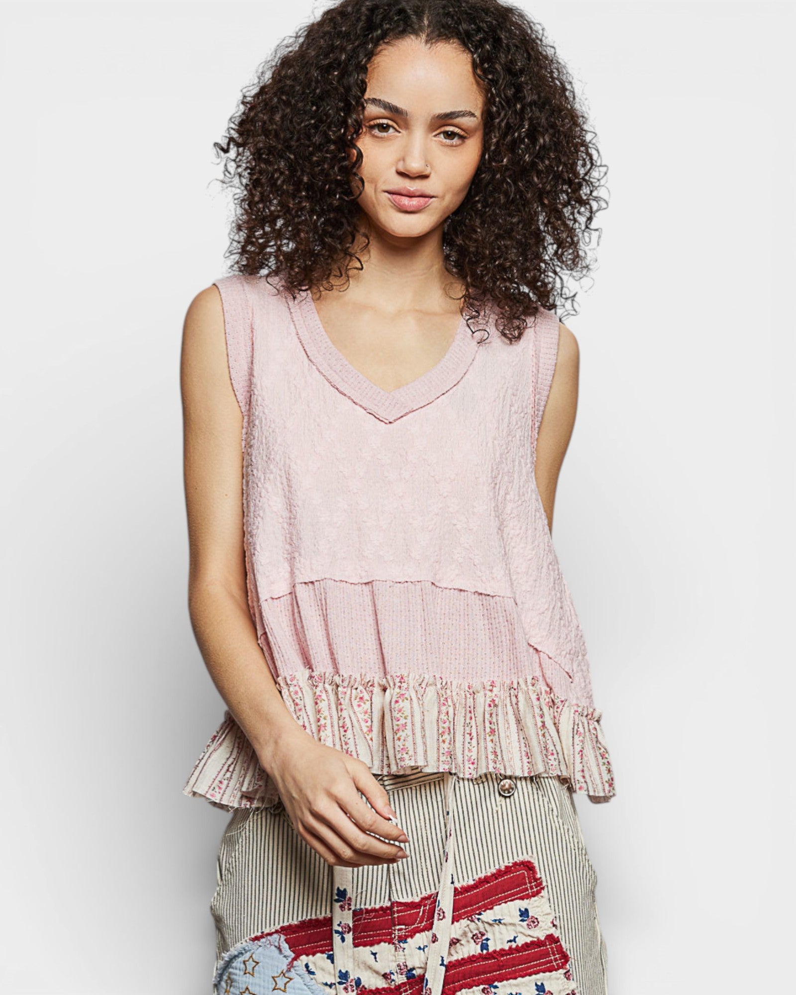 Woman wearing a pink layered top with a plain background