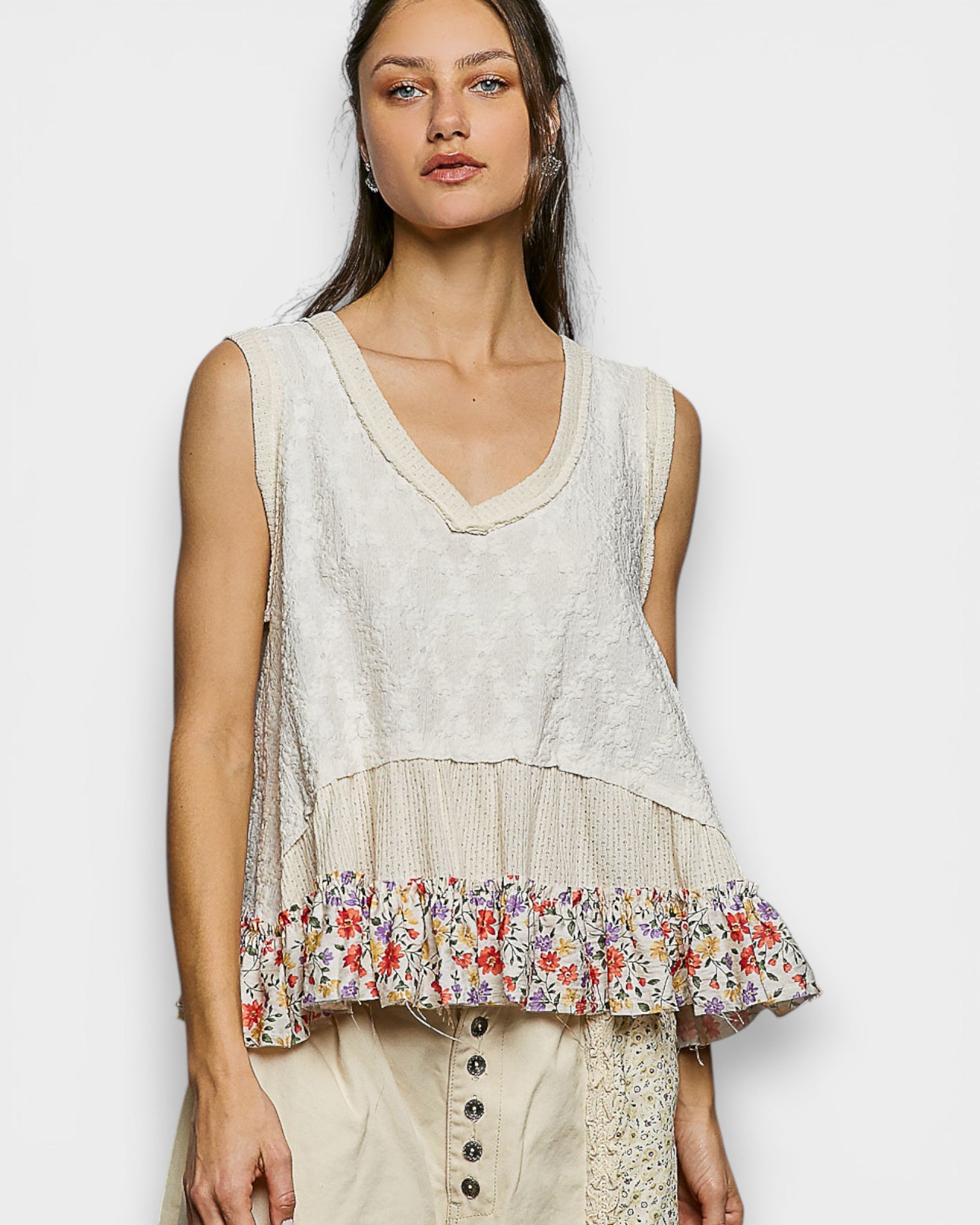 Woman wearing a sleeveless top with floral hem on a white background