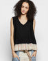 Woman wearing a black sleeveless top with a floral hem against a white background