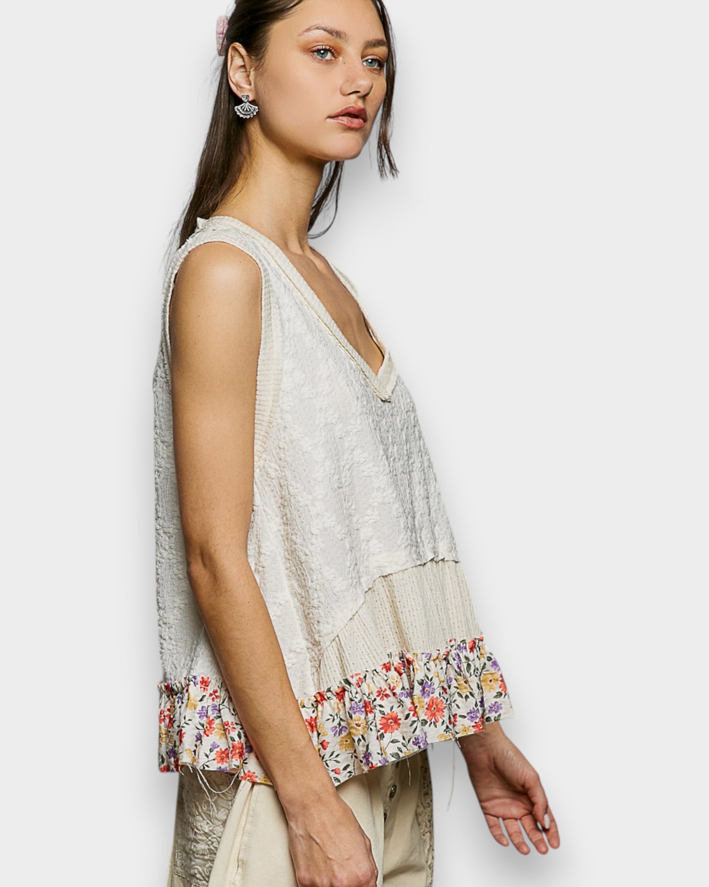 Woman wearing a sleeveless top with floral hem on a white background