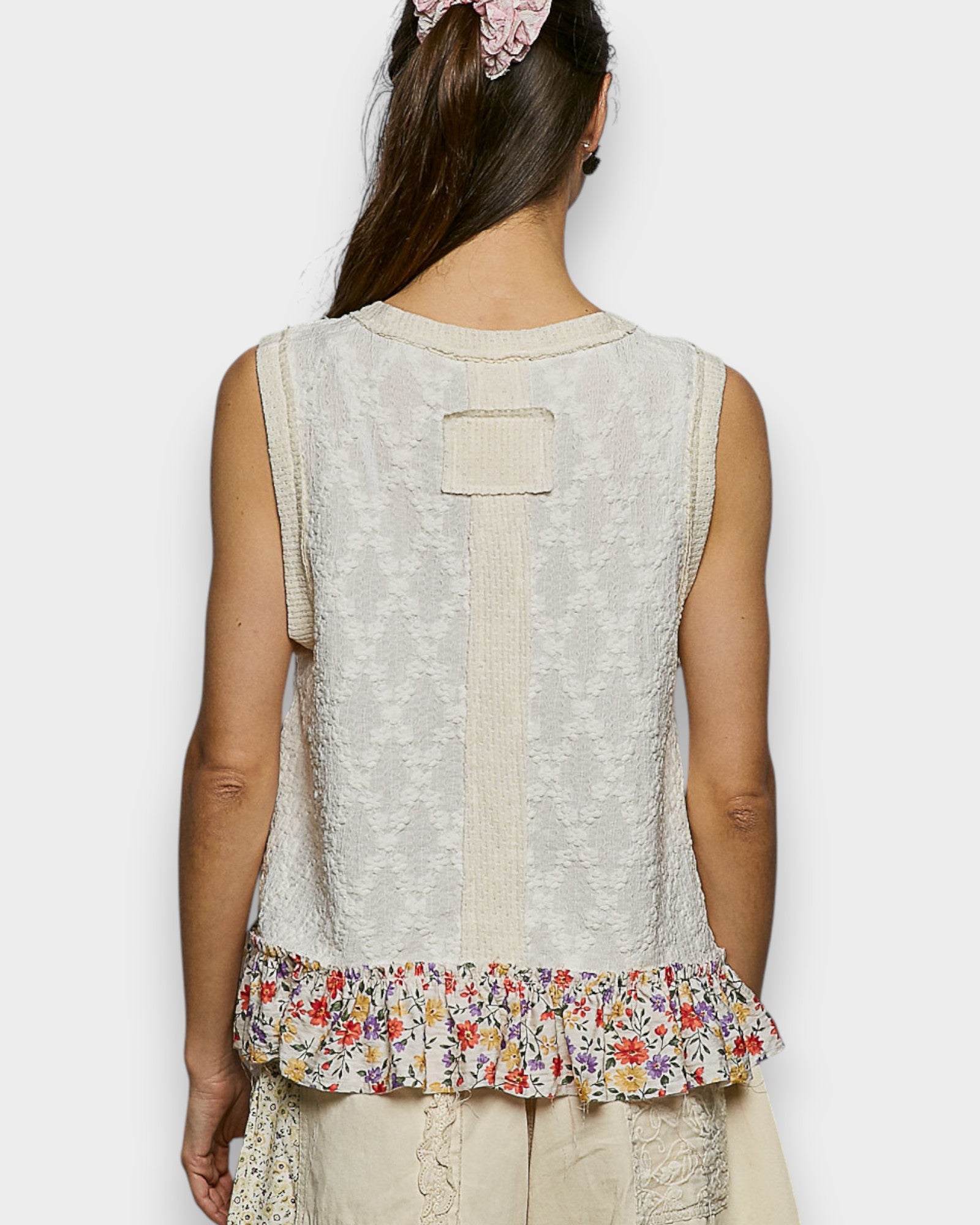 Woman wearing a sleeveless top with floral hem on a white background