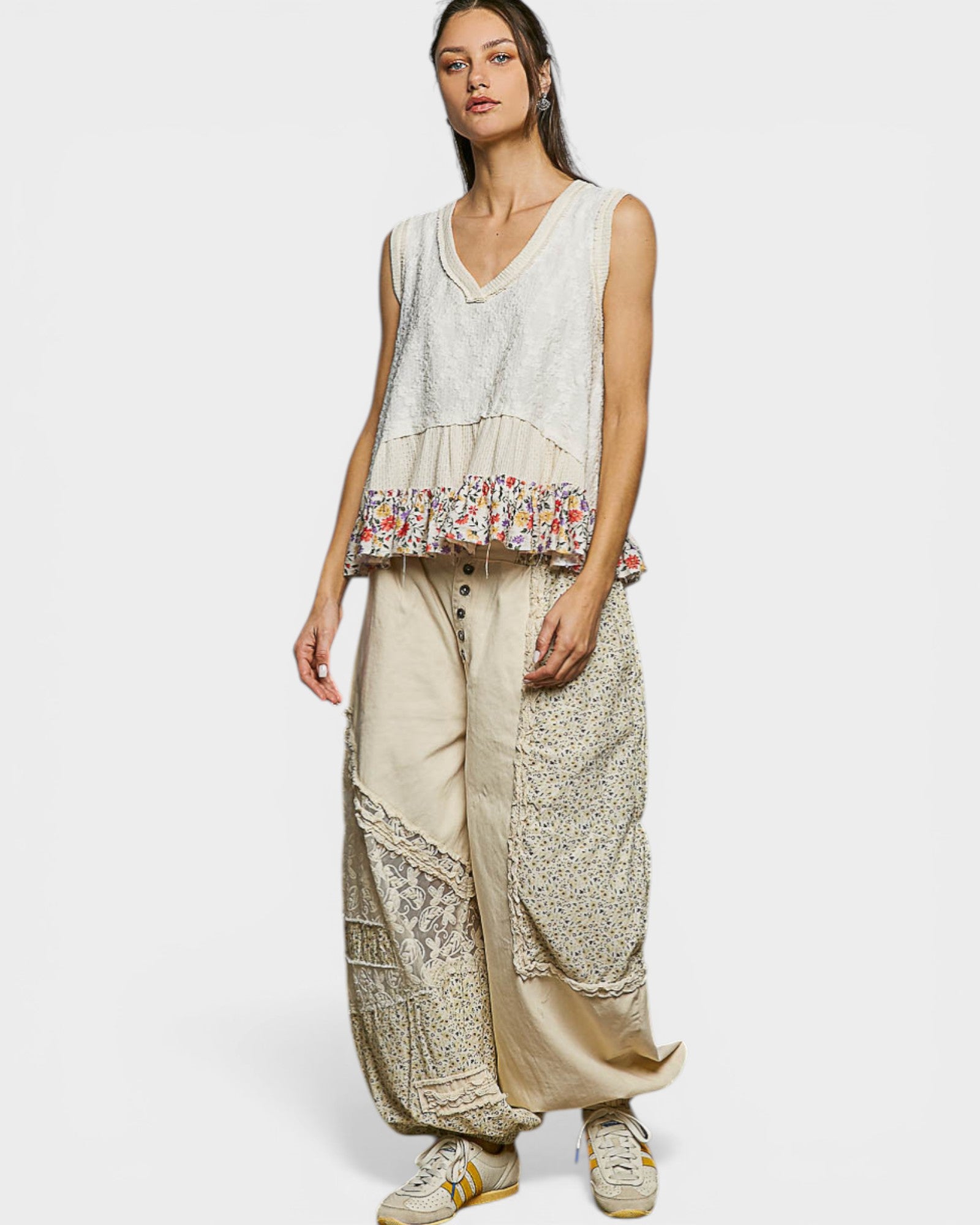 Woman wearing a sleeveless top with floral pattern and wide-leg pants on a white background